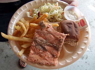 plate of food including salmon, french fries, coleslaw and a roll